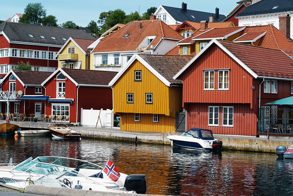 Closeup shot of houses by the river at Kragero, Telemark, Norway with boats parked in the water Closeup shot of houses by the river at Kragero, Telemark, Norway with boats parked in the water